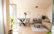 Lyst og moderne opholdsstue i en lodge på Zomerlicht i Nederlandene med planter, sofa og spisebord.
