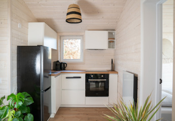 Moderne lille køkken med sort køleskab, kaffemaskine og planter på en lodge ved Slowlodge 2, Zomerlicht.