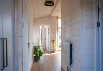 Lys gang i træ, planter i potter og sollys ved Slowlodge 2, Zomerlicht, Nederlandene.