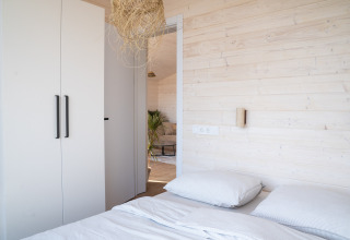 Camera da letto luminosa e minimalista alla Slowlodge 2 di Zomerlicht, Paesi Bassi, con pareti in legno chiaro.