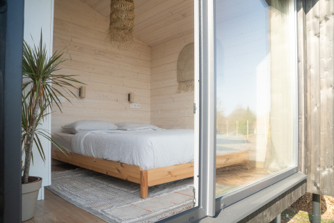 Camera luminosa in legno con letto matrimoniale a Slowlodge 2, Zomerlicht, Paesi Bassi, vista dalla porta.