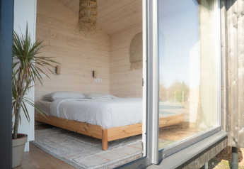 Lyst og hyggeligt soveværelse i træ på Slowlodge 2 ved Zomerlicht, Holland, set udefra gennem glasdør.