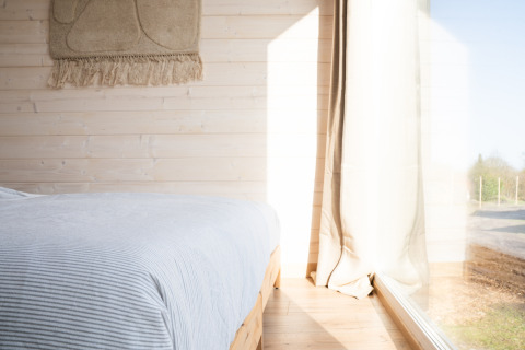 Camera luminosa a Slowlodge 2 a Zomerlicht nei Paesi Bassi con pareti in legno e grande finestra.