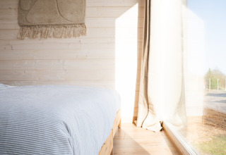 Camera luminosa a Slowlodge 2 a Zomerlicht nei Paesi Bassi con pareti in legno e grande finestra.