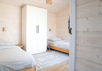 Lyst dobbeltværelse med trævægge, to enkeltsenge, et hvidt garderobeskab og et tæppe i Slowlodge 2, Zomerlicht.