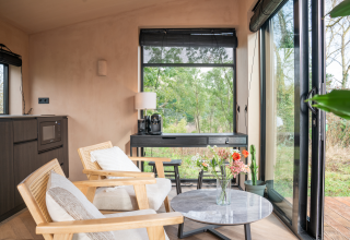 Lichte, moderne lodge-inrichting bij Slowcabin in Zomerlicht, Nederland, met grote ramen en tuinzicht.