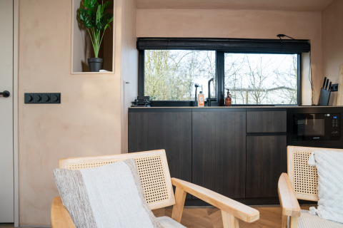 Modern interieur in lodge 'Slowcabin' te Zomerlicht, Nederland, met donker meubel en groot raam.