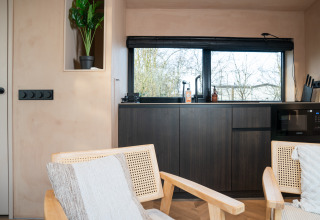 Modern interieur in lodge 'Slowcabin' te Zomerlicht, Nederland, met donker meubel en groot raam.