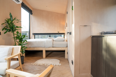 Gezellig, licht interieur van een Slowcabin-lodge in Zomerlicht, Nederland, met planten en houten meubels.