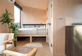 Gezellig, licht interieur van een Slowcabin-lodge in Zomerlicht, Nederland, met planten en houten meubels.