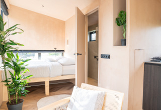 Lichte, minimalistische slaapkamer in Slowcabin bij Zomerlicht, Nederland, met planten en natuurlijk licht.