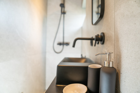 Minimalistische badkamer met zwarte kraan en zeepdispenser in Slowcabin bij Zomerlicht, Nederland.