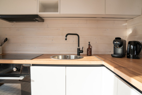 Moderne kitchenette met houten blad, zwarte kraan, koffiemachine en waterkoker bij Slowlodge Sage, Zomerlicht.
