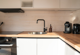 Moderne kitchenette met houten blad, zwarte kraan, koffiemachine en waterkoker bij Slowlodge Sage, Zomerlicht.