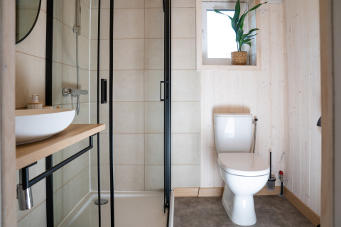 Moderne badkamer bij Slowlodge Sage bij Zomerlicht in Nederland met douche, toilet en wastafel.