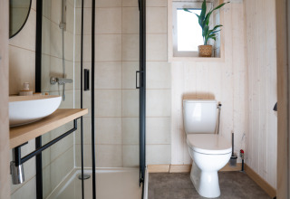 Moderne badkamer bij Slowlodge Sage bij Zomerlicht in Nederland met douche, toilet en wastafel.