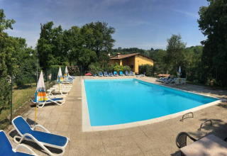 Outdoor swimming pool with sun loungers and umbrellas at Agriturismo Le Sorgive e Le Volpi, Lombardy, Italy.