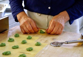 Iemand maakt verse ravioli met groene vulling op een houten werkblad in een Italiaanse keuken in Lombardije.
