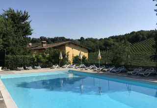 Piscina al aire libre con tumbonas en Agriturismo Le Sorgive e Le Volpi, rodeada de colinas verdes en Lombardía, Italia.