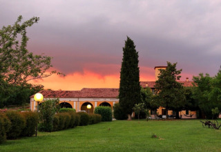 Solnedgang over Agriturismo Le Sorgive e Le Volpi i Lombardiet, Italien, med grønne haver og lamper