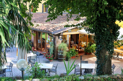 Espace repas extérieur à l’Agriturismo Le Sorgive e Le Volpi, entouré de verdure en Lombardie, Italie.