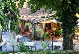 Udendørs spiseområde på Agriturismo Le Sorgive e Le Volpi, omgivet af grønne træer i Lombardiet, Italien.