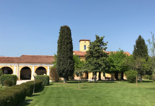 En solrig dag i Agriturismo Le Sorgive e Le Volpi i Lombardiet, Italien, med grønne plæner og træer.
