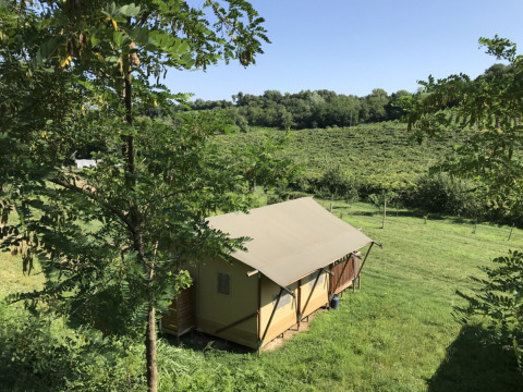 Ferienzelt auf dem Agriturismo Le Sorgive e Le Volpi in der Lombardei, Italien, umgeben von grüner Landschaft.