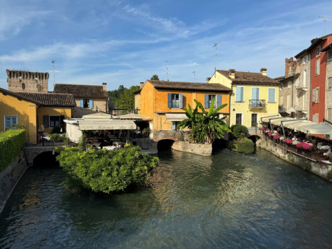 Kleurrijke gebouwen aan het water bij Agriturismo Le Sorgive e Le Volpi, Vodatent, Lombardije, Italië op zonnige dag.