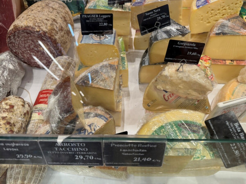 Et udvalg af oste og pålæg bag glas i en delikatessebutik i Lombardiet, Italien, set fra oven.