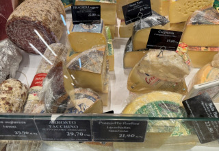 Selección de quesos y embutidos detrás de un vidrio en una tienda en Lombardía, Italia, vista desde arriba.