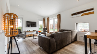Moderne stue med store vinduer, brun sofa og elegant indretning på Schaelsbergerbosch Garden House i Holland.