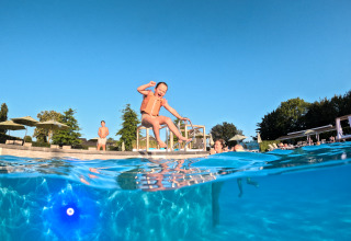 Kindje springt blij het zwembad in met een zwemvest bij Schaelsbergerbosch, Resort Mooi Bemelen.