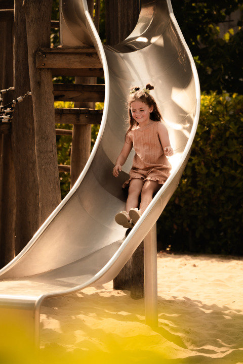 Een kind speelt op de glijbaan bij Schaelsbergerbosch - Garden House & in Resort Mooi Bemelen, Nederland.