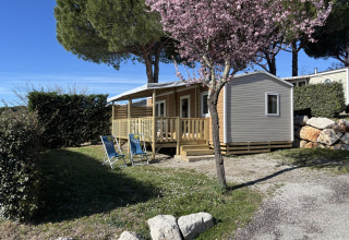 Mobil-home « New Horizon » au Flower Camping Provence Vallée en France, entouré de verdure et arbres en fleurs.