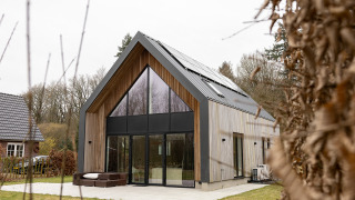 Lodge Forest villa Zoethout con fachada de madera, grandes ventanales y paneles solares en entorno natural.