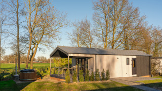 Vista sulla lodge Weideblik met hottub con terrazza, vasca idromassaggio e alberi circostanti.
