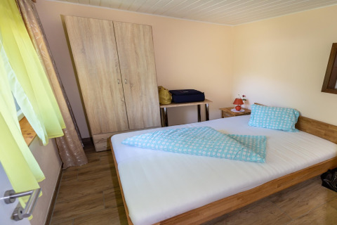 Soveværelse i Blasge Bungalow 1 i Østrig med dobbeltseng, klædeskab, natbord og vindue med lyse gardiner.