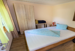 Soveværelse i Blasge Bungalow 1 i Østrig med dobbeltseng, klædeskab, natbord og vindue med lyse gardiner.
