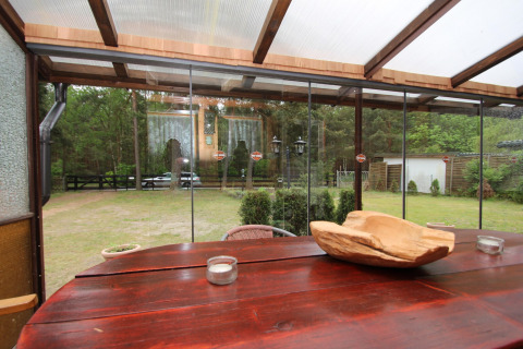 View from the covered terrace at Holiday home Susanne 58 qm with wooden table and garden in Germany.