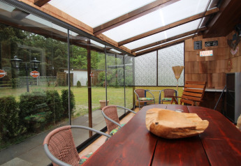 Cozy sunroom in Holiday home Susanne, Germany, with wooden table, chairs, and garden view outside.
