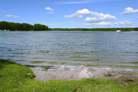 Zicht op het meer bij Holiday home «Susanne 58 qm» in Duitsland met gras, water en blauwe lucht.