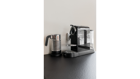 Macchina da caffè e montalatte su tavolo nero presso Forest villa «De Bosburcht» a De Kremmer, Paesi Bassi.