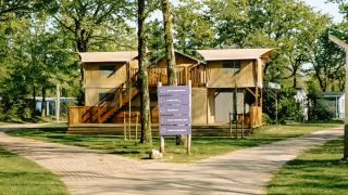 Foto vom Treehouse Tent mit Whirlpool, umgeben von Bäumen und grünen Wegen in ruhiger Natur.