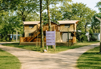 Billede af Treehouse Tent med boblekar, omgivet af træer og grønne stier i et fredeligt område.