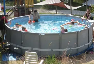 Bambini e adulti si divertono in una piscina fuori terra circolare al Campeggio Les Trexons, Grand Est, Francia.