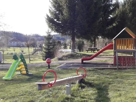 Parco giochi al campeggio Les Trexons con scivoli, altalena e tavoli da picnic in Grand Est, Francia.