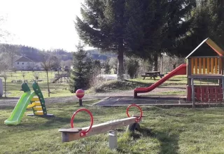 Parco giochi al campeggio Les Trexons con scivoli, altalena e tavoli da picnic in Grand Est, Francia.