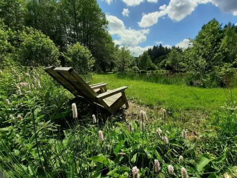 Sdraio in legno su un prato verde al campeggio Les Trexons, Grand Est, Francia, in una giornata soleggiata.