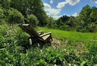 Sdraio in legno su un prato verde al campeggio Les Trexons, Grand Est, Francia, in una giornata soleggiata.